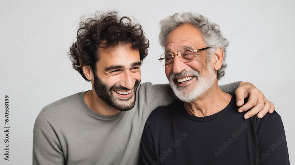 Le portrait d'un père et son fils souriants et heureux sur un fond isolé gris. Le portrait d'un père et son fils souriants et heureux sur un fond isolé gris.
