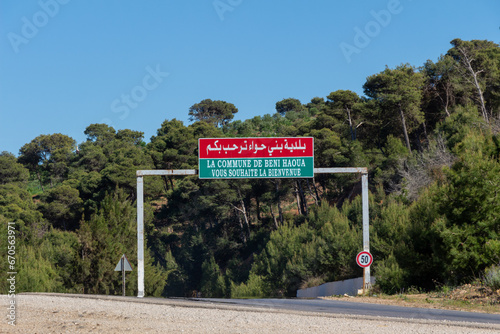 Entry of the village of Beni Haoua on the costal road between Cherchell and Damous, Algeria. Town sign, blue sky, mountain. photo