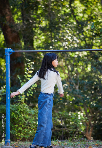 秋の公園で鉄棒を遊んでいる小学生の女の子の様子