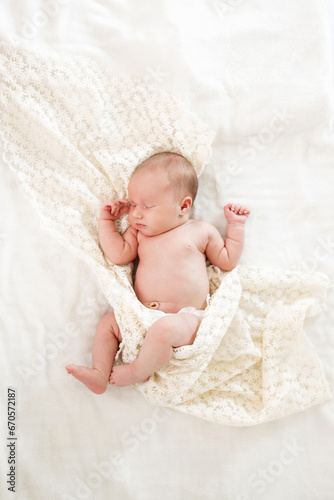 Sleeping newborn baby wrapped on a white blanket. Beautiful portrait of a little girl one week.