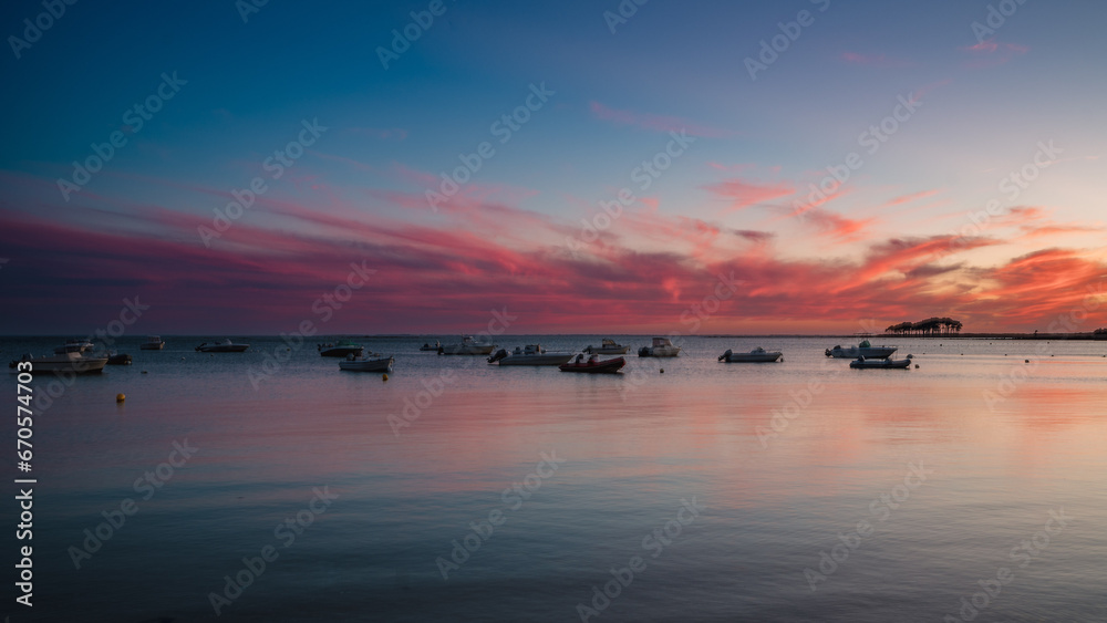 Ships sailing at sea during a colourful sunset