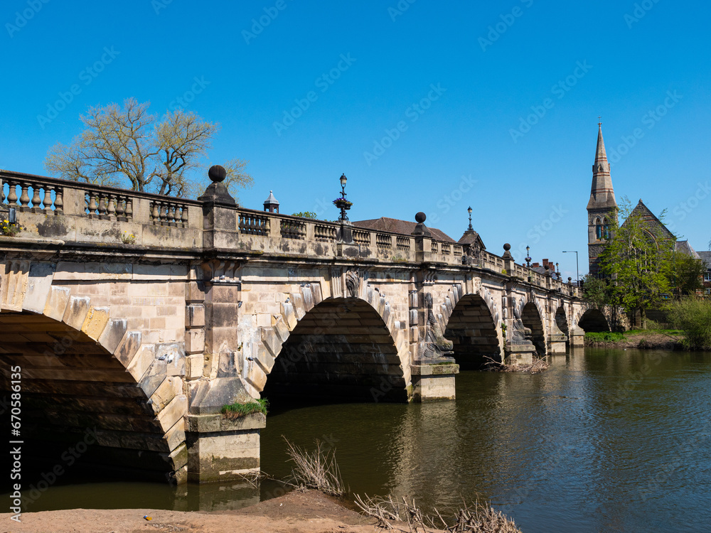 The stone arches of the 18th century Grade II listed English Bridge which crosses the River Severn in Shrewsbury, UK. Clear blue sky. Space for text.