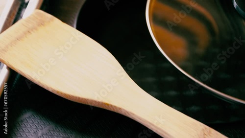 Cinematic close up of an electric shabu pan or an electric griddle with a glass lid top and a wooden spatula utensil photo