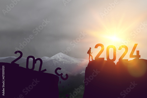 Silhouette sport man with 2023 and 2024 number new year on sunset sky at top of mountain abstract background. Happy new year and holiday celebration concept. Vintage tone filter color style. High