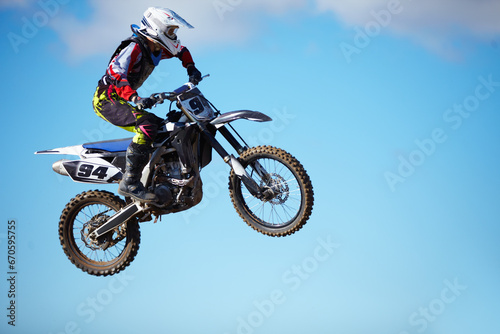 Person, motorcycle and air jump stunt as professional in action danger, competition or fearless in sky. Bike rider, off road transportation or fast speed adventure or rally, extreme sports challenge