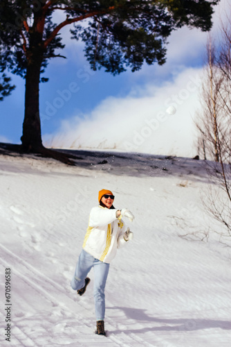 a woman in a good mood in winter on a walk., sunny day, playing snowballs, throwing snow at each other, spontaneity