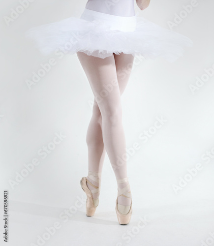 Ballet dancer, legs and pointe shoes closeup in studio white background for performance, practice or balance. Female person, feet or tutu for artistic expression training, elegant or creative workout