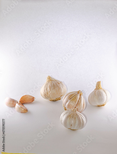 Three whole bulbs of garlic heads and three separated cloves arranged in a triangle and a propeller shape. Side view macro photograph isolated on a white background.High quality HD details. photo