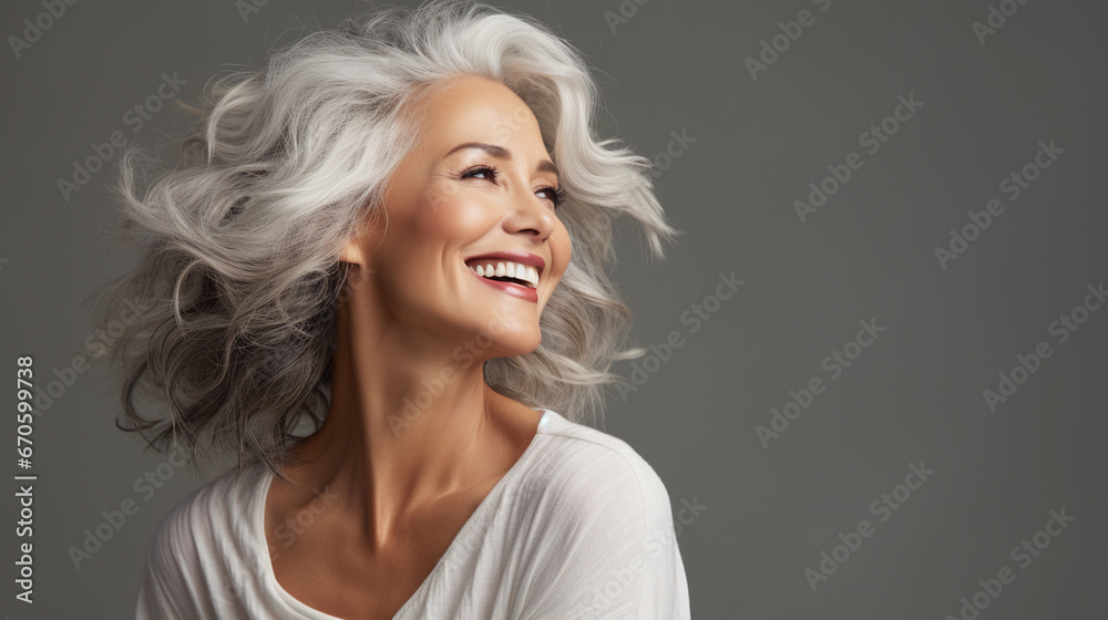 A beautiful middle-aged woman with gray hair and healthy skin is smiling in a good mood. 