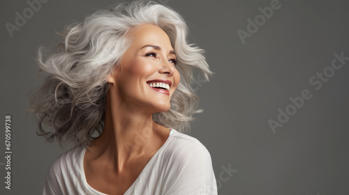 A beautiful middle-aged woman with gray hair and healthy skin is smiling in a good mood. 