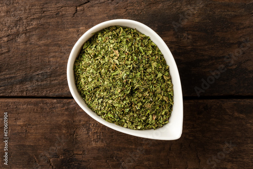 Dried lovage in bowl on retro wooden background. Top view photo