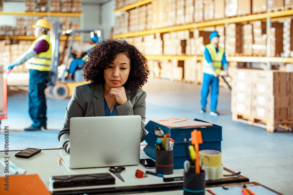 Focused Warehouse Manager Working on Her Laptop Focused Warehouse Manager Working on Her Laptop