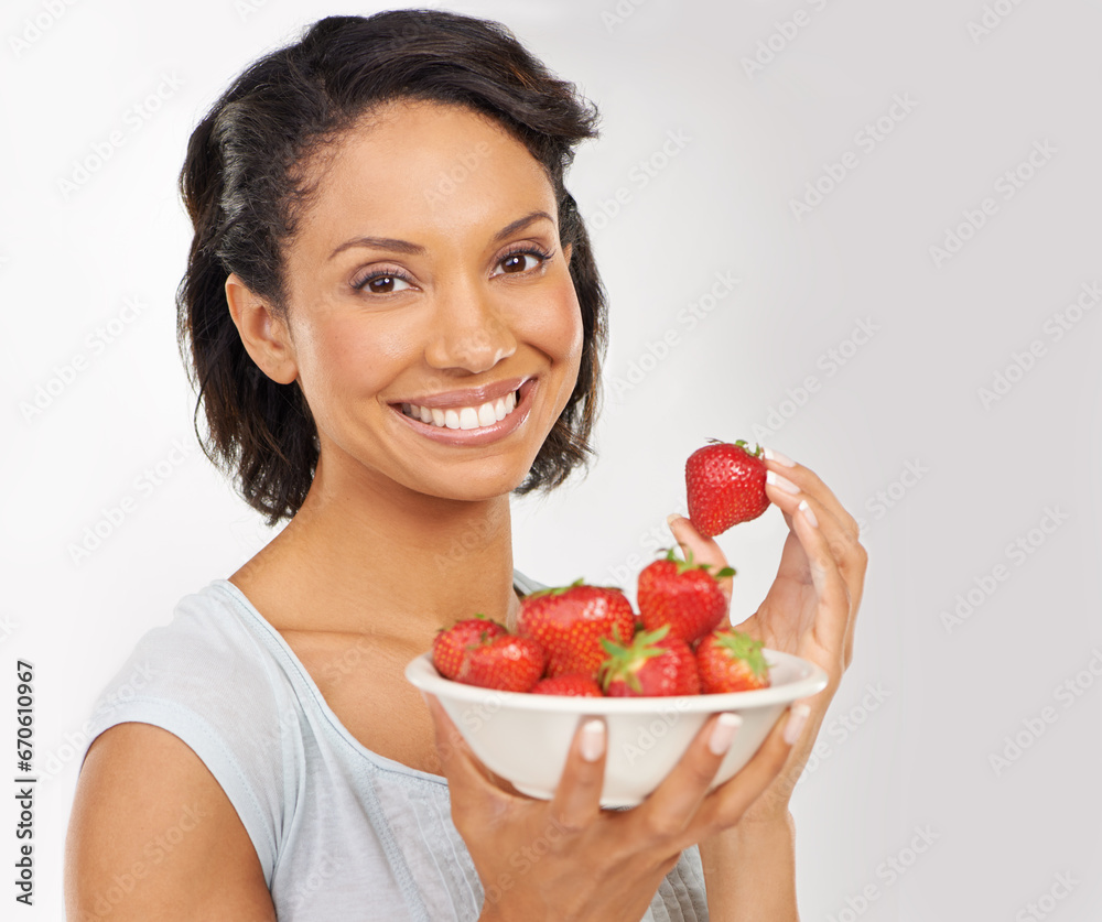 Health, strawberries and portrait of woman in a studio for wellness, nutrition and organic diet. Smile, vitamins and female person from Mexico eating fruit for healthy vegan snack by gray background. Health, strawberries and portrait of woman in a studio for wellness, nutrition and organic diet. Smile, vitamins and female person from Mexico eating fruit for healthy vegan snack by gray background.