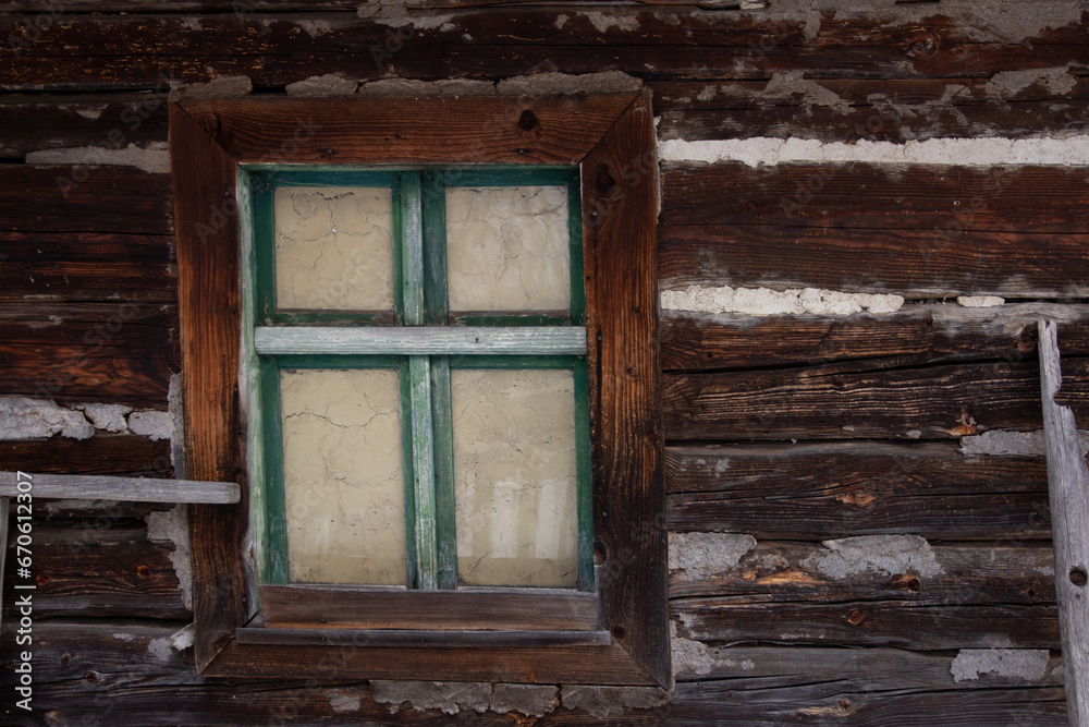 The window in the log cabin has a sturdy wooden frame, providing a rustic and natural appeal to the space.