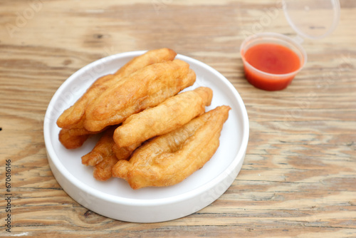 Cakwe or You tiao is a long golden-brown deep-fried strip of dough or typical chinese doughnut. Served in white plate photo