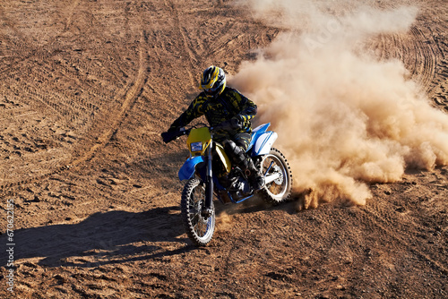 Man, motorcycle and bike dust cloud as professional rider in action danger competition, fearless or race. Male person, transportation or fast speed dirt adventure or rally, challenge gear or driving