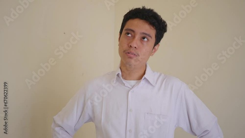 Indonesian office employee wear white clothes feel stress and unhappy expression. The footage is suitable to use for man expression and daily life content media.
