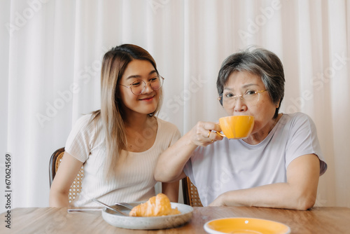 Asian old woman mother and adult daughter eating croissant bakery and drink coffee at cafe, spending happy life time together.