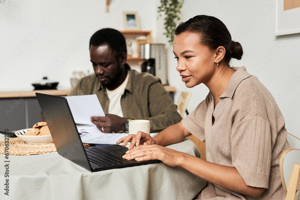 Side view portrait of Black young couple managing household together and doing taxes, copy space Side view portrait of Black young couple managing household together and doing taxes, copy space