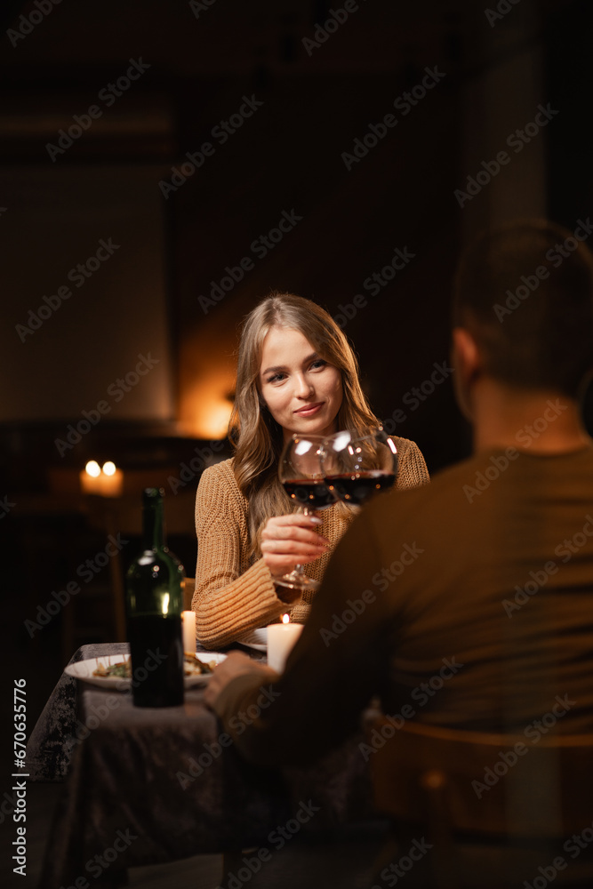Happy young couple having romantic dinner with candles and red wine at home