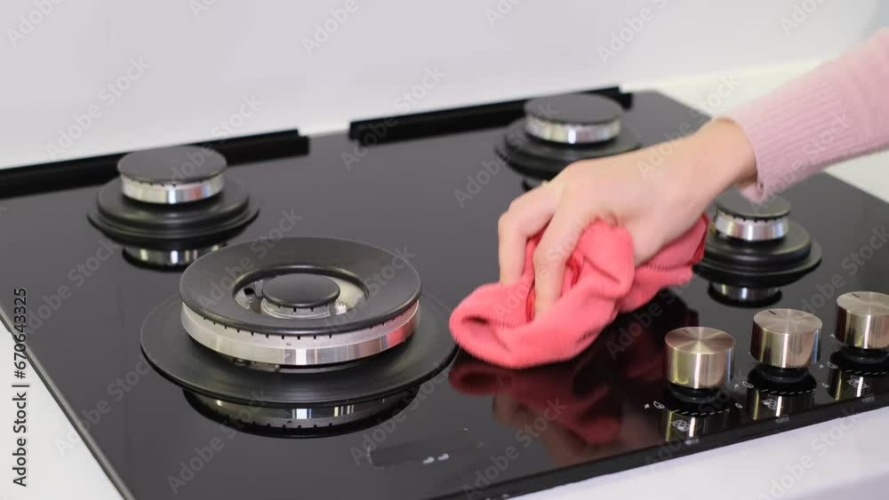 A woman cleans, polishes a stove, close-up, no face. Housework and housekeeping concept. A woman cleans, polishes a stove, close-up, no face. Housework and housekeeping concept.