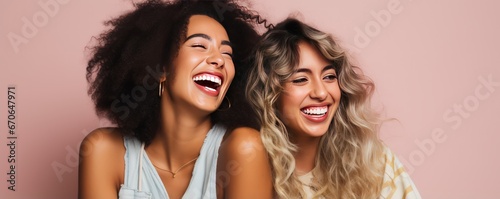 Scandinavian women smiles widely showing teeth alongside European girl friend. Cheerful best friends laugh together posing for photo. Young women of different races support each other