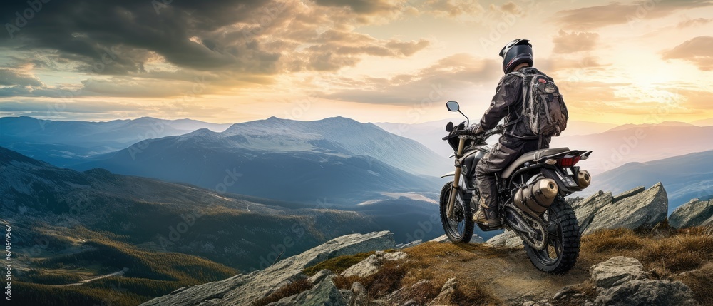 fearless biker perched at the edge of a rugged mountain cliff - obrazy, fototapety, plakaty 