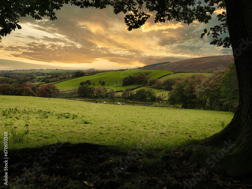A view across open farm land in Lancashire UK with a low sun in the autumn and the hills behind