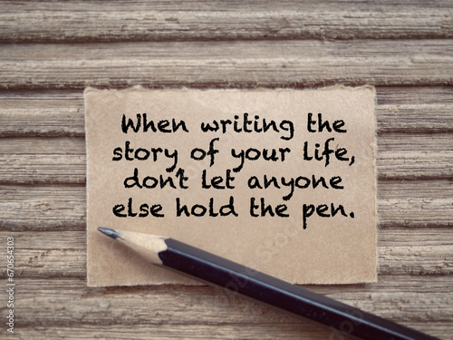 Motivational and inspirational wording. When Writing The Story Of Your Life, Don’t Let Anyone Else Hold The Pen written on a paper. With blurred styled background.