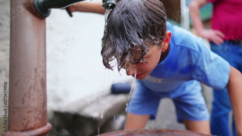 Photos Young boy washing head and hair at public fountain street in Europe during hot summer day