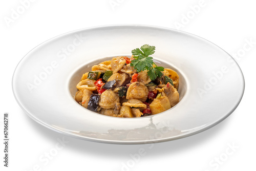 Orecchiette pasta cooked topped with eggplant and zucchini and tomato sauce and with parsley leaves in white plate isolated