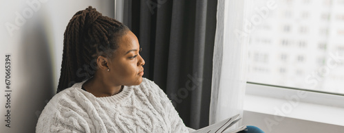 Banner african american young woman looking out of the window on winter weather, copy space