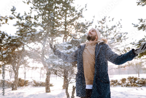 Young stylish man in a snowy forest. Handsome man enjoying sunny winter weather. Concept of people, vacation.