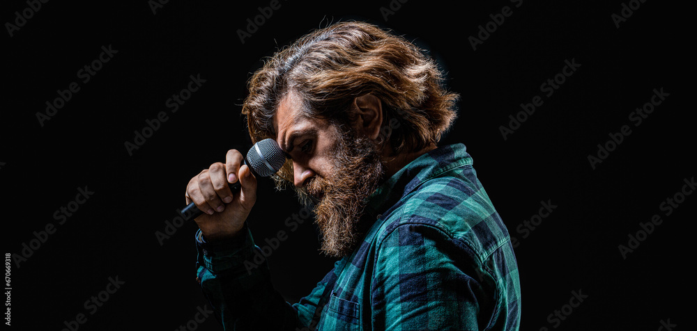 Male singing with a microphones. Man with a beard holding a microphone and singing. Bearded man in karaoke sings a song into a microphone. Bearded man singing with microphone Male singing with a microphones. Man with a beard holding a microphone and singing. Bearded man in karaoke sings a song into a microphone. Bearded man singing with microphone