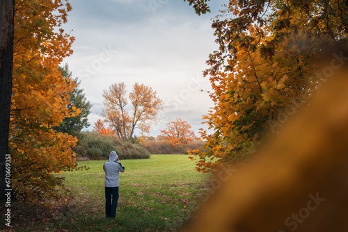 Young man holding his white hoodie and standing in autumn Czech landscape © Space Creator