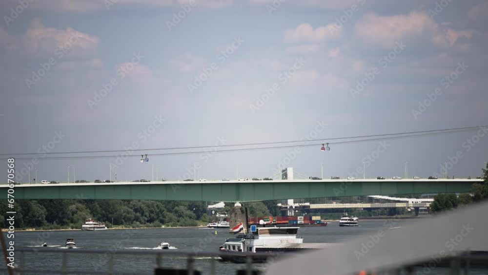 Boat and vehicle traffic on Rhein river and Zoo bridge in Cologne, Germany with Seilbahn cabin lift at background Boat and vehicle traffic on Rhein river and Zoo bridge in Cologne, Germany with Seilbahn cabin lift at background