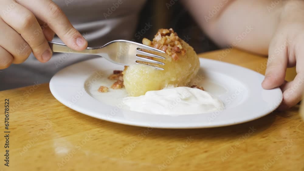 A man eats zeppelins served in a plate with sour cream in a restaurant. Close-up A man eats zeppelins served in a plate with sour cream in a restaurant. Close-up