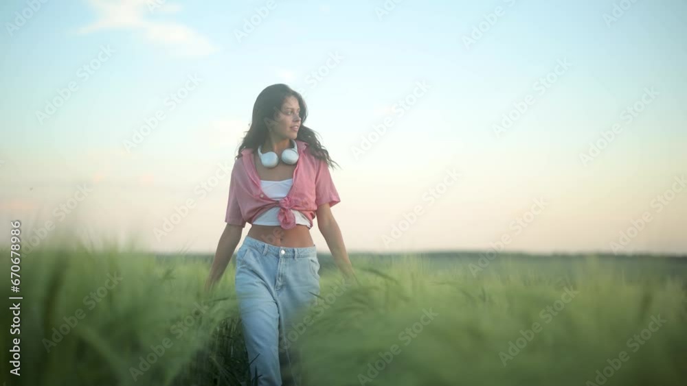 A young woman happily running in slow motion through a field touching with hand wheat ears. Beautiful carefree girl enjoying nature and sunlight in wheat field at incredible colorful sunset A young woman happily running in slow motion through a field touching with hand wheat ears. Beautiful carefree girl enjoying nature and sunlight in wheat field at incredible colorful sunset
