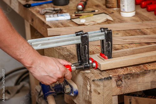 Carpenter clamps are fixed to boards. Gluing joinery in workshop