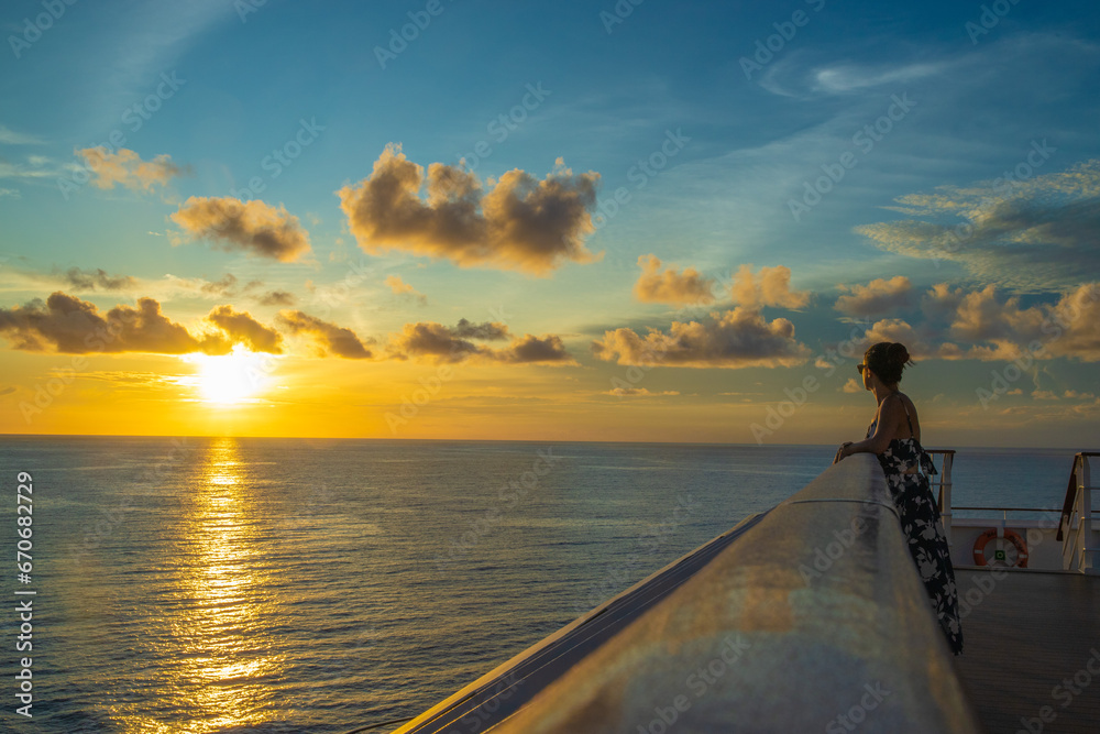 Fototapeta premium A woman standing on a deck looking out at the ocean