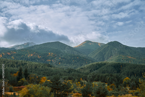 View of the Pirin Mountains on an autumn day, the change of seasons and the forest brightly colored in autumn colors. Idea for background or banner about travel and outdoor recreation, copy space