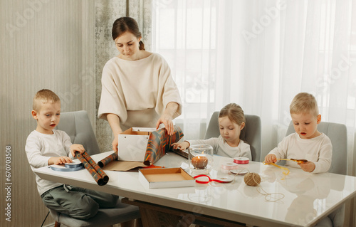 A mother and her children are preparing for Christmas, packing gifts.