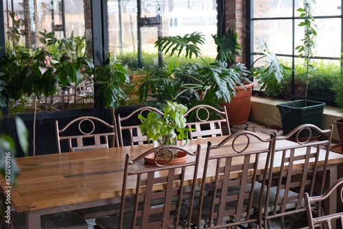 Restaurant with wooden and metal furniture, big windows and plants