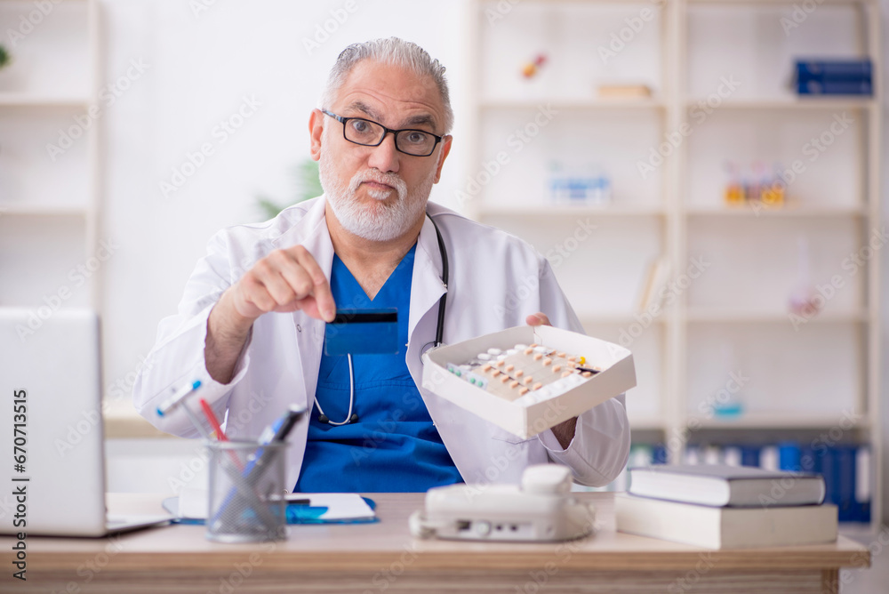 Old male doctor holding credit card Old male doctor holding credit card