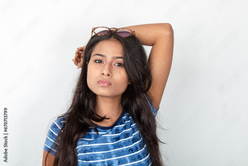 Studio shot of a young, beautiful Indian female model in casual wear, wearing blue and white printed top and a clear eyeglass against white background. Advertisement shoot. Eyeware product shoot. Studio shot of a young, beautiful Indian female model in casual wear, wearing blue and white printed top and a clear eyeglass against white background. Advertisement shoot. Eyeware product shoot.