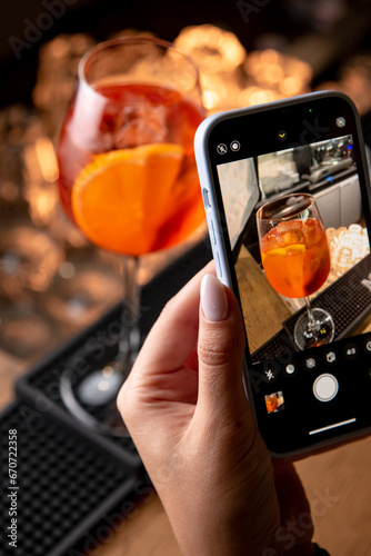 girl takes a photograph of a cocktail at a restaurant bar, close-up