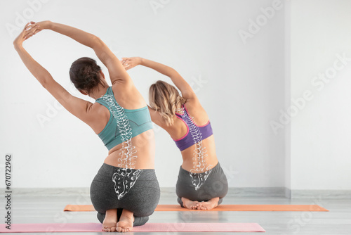 Schilderij op canvas Sporty young women doing yoga in gym. Concept of healthy spine
