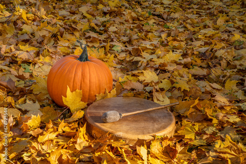 native American style drum with pumpkin on a backyard lawn covered by golden maple leaves, fall scenery photo