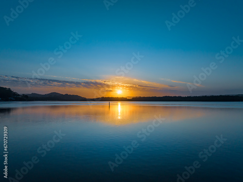 Sunrise waterscape with a scattering of clouds and reflections