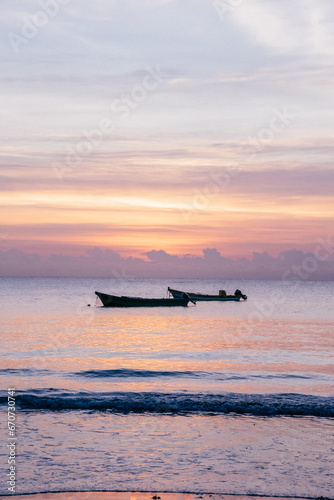 Serene sunset over calm sea with anchored boats in Tulum